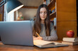© Vitalii - Portrait of a young girl working in university library, getting ready for next classes, reading literature. Female student studying in library