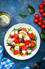 Wall Mural - Tasty Greek salad with feta cheese, kalamata olives, tomatoes, paprika, cucumber and onion, healthy mediterranean food. Blue table background, top view