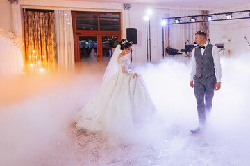 the first dance at the wedding of the bride and groom in an elegant restaurant with great lighting and atmosphere. Heavy smoke