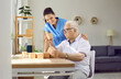 © Studio Romantic - Friendly nurse helping demented old man in retirement home. Senior man with cognitive problems sitting at desk and building wood block house. Dementia care, people with Alzheimer's disease concept