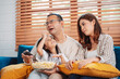 © Kiattisak - Asian Family consisting of parents, happy daughter watching TV or movie eating popcorn on sofa in living room at home. enjoy relaxing happiness.