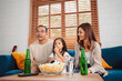 © Kiattisak - Asian Family with daughter watching sport football cheering excited eating popcorn on sofa in living room at home. enjoy relaxing happiness.