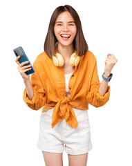 Cheerful young Asian woman in headphones and holding smartphone with fists clenched celebrating victory expressing success on background.