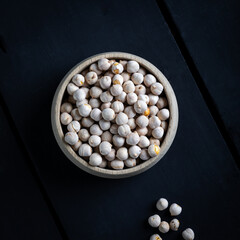 Wall Mural - Roasted white chickpeas in wooden bowl, traditional Turkish nut on dark background. Turkish leblebi, famous nut, stack of yellow white roasted chickpea.