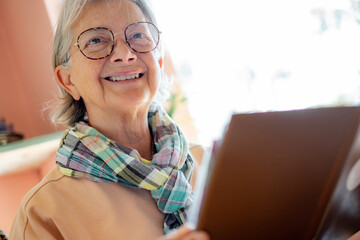 Wall Mural - Smiling senior woman wearing eyeglasses relaxing at cafe table reading menu, leisure time