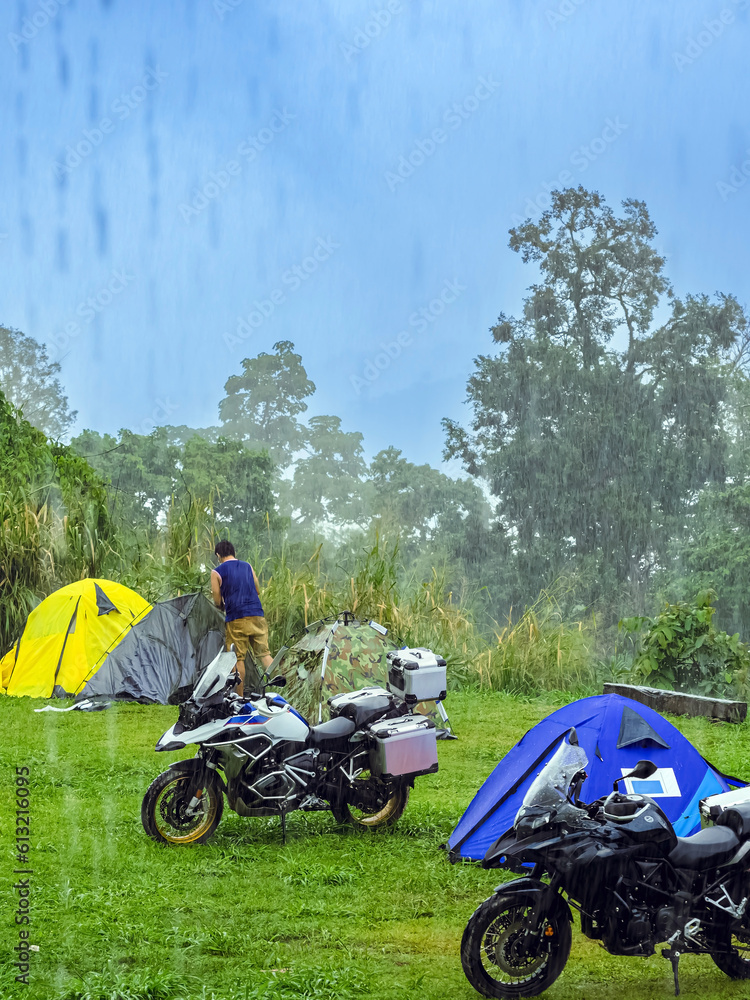 Back view of Asian male traveler tying tents with ropes to keep them ...