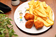 Nuggets with potato fries on a white plate, close-up, selective focus. Lunch, child portion.