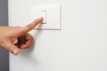 Turn off the light, close up finger man hand is closing the power switch with wall at home  to save energy. reduce global warming.