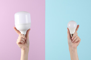 Female hands hold two led light bulbs on a blue-pink background