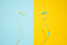 Blue And Yellow Wired Earphones On Blue Yellow Background. Top View