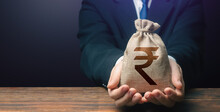 Businessman Holds Out Indian Rupee Money Bag. Getting A Grant. Easy Money. Salary, Benefits, Profit. Attracting Investments. Deposit Savings. Cashback. Banking And Crediting. Mortgage, Loan Approval.