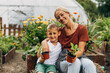 © cherryandbees - Front view of mother and her son holding vegetable seedling in their eco garden.