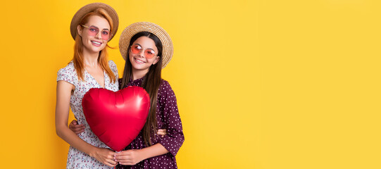 Canvas Print - Mother and daughter kid banner, copy space, isolated background. cheerful mother and daughter holding love heart balloon on yellow background.