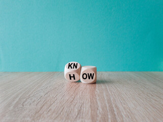 Know how and business concept. Turned cube and changed the word 'how' to 'know'. Beautiful wooden table, blue background. Copy space.