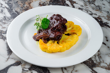 Wall Mural - Fried beef fillet steak in sauce with cauliflower and microgreens in a plate.