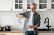 © Prostock-studio - Thirsty Senior Man Pouring Water From Jug To Glass In Kitchen Interior
