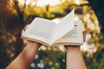 Wall Mural - Open book on a sunset background. Reading, studying, school. Read a book outdoors