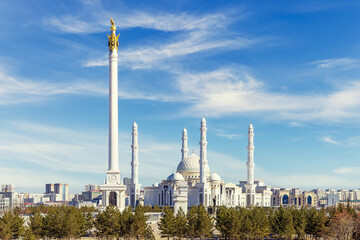 The Hazrat Sultan Mosque and the Kazak eli Monument in Astana, against the backdrop of a picturesque blue sky with light clouds. Cityscape of Astana aka Nur-Sultan. Wallpaper or postcard