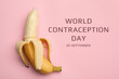 World contraception day. Banana with condom on pink background, top view