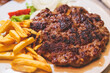 Pljeskavica with french fries on a plate, traditional serbian dish, grilled dish of spiced meat patty mixture of pork, beef and lamb, popular balkan steet food Pleskavitza, served in cafe