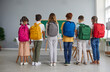 Preparation for school. Junior high school students show off their large, roomy, colorful and fashionable backpacks. Children stand in row with their backs to camera with school bags on shoulders.