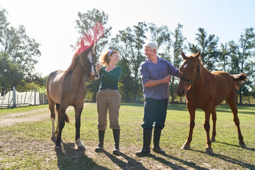 Man and woman holding two horses on farm ranch