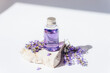 Lavender oil in transparent bottle on stone podium in sunlight. Natural cosmetics, aromatherapy concept. Closeup