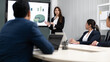 © Nassorn - Businesswoman standing in conference room giving statistic presentation. Young Asian professional business woman talking, presenting strategy planning to executive working team in corporate meeting.
