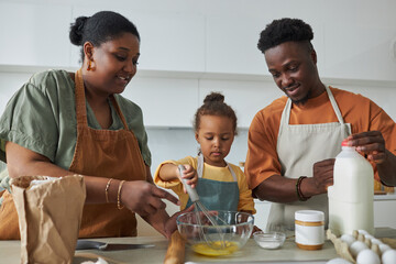 Wall Mural - African American family baking together with their little daughter in the kitchen