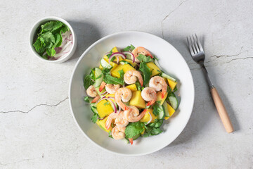 Healthy food shrimp salad has mango cucumber peppermint in bowl on slate background.