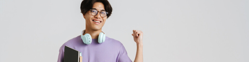 Wall Mural - Young handsome smiling asian boy with headphones on his neck