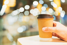 A Man's Hand Holding A Cup Of Coffee In The Morning With Red Brick Background. Concepts Of Lifestyle Coffee Shop Is The Perfect Place To Meet Family Or Friends For A Relaxing Breakfast.