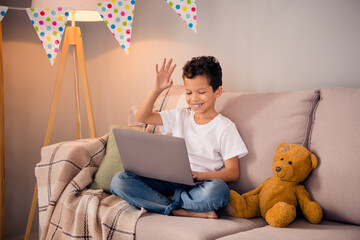 Sticker - Photo of cute boy school kid connected to online lesson answer teacher question say hello classmates in modern nursery room