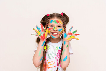 Wall Mural - A little girl shows her palms painted with multicolored paints and smiles. A schoolgirl artist draws with her own hands. Creative education of children. White isolated background.