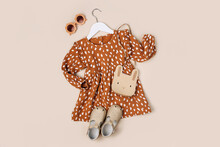 Stylish Kids Dress With Cute Handbag And Shoes On A Hanger On A Beige Background. Fashion Kids Outfit And Accessories For Summer Or Autumn.