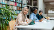 © pikselstock - Multiethnic group of students sitting in a library and studying together