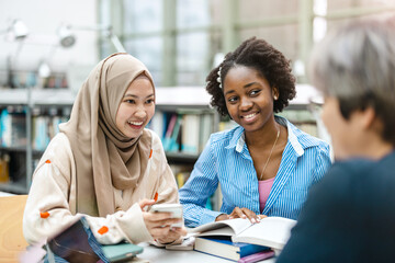 Wall Mural - Multiethnic group of students sitting in a library and studying together
