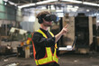 © amorn - Male factory mechanic using virtual reality headset. Male engineer working or using virtual reality headset for checking machinery in industry factory and wearing safety uniform and helmet