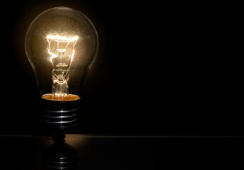 an incandescent light bulb is burning on a black background.