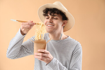 Poster - Young man eating tasty Chinese food on beige background