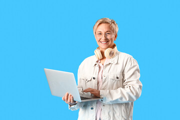 Mature female programmer working with laptop on blue background