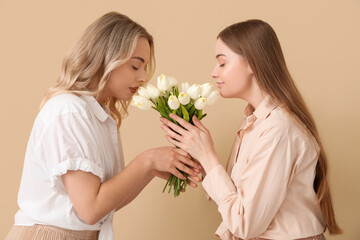 Wall Mural - Young sisters with tulips on beige background