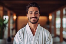 Portrait of handsome young man in bathrobe looking at camera while standing in spa salon