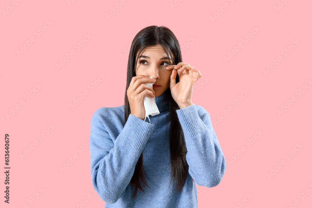 Allergic young woman with tissue on pink background