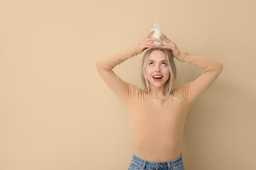 Poster - Young woman with glass of milk on beige background