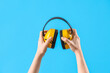 Female hands holding ear muffs on blue background