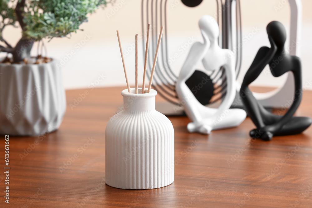 Bottle of reed diffuser, houseplant and decor on table in room, closeup
