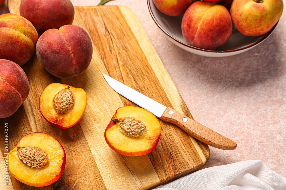 Board and bowl with sweet peaches on pink background