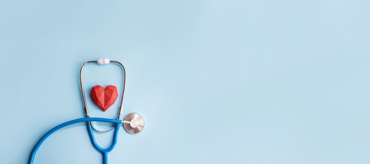 Blue stethoscope and red polydiagonal decorative heart on pastel background. Medical banner. Doctor's day concept. Selective focus, copy space