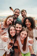 © Jose Calsina - Vertical portrait. Group of best friends on a rooftop wine party. Young people drinking, toasting glasses, laughing and having fun on a friendly meeting, enjoying happy hour at winery bar restaurant